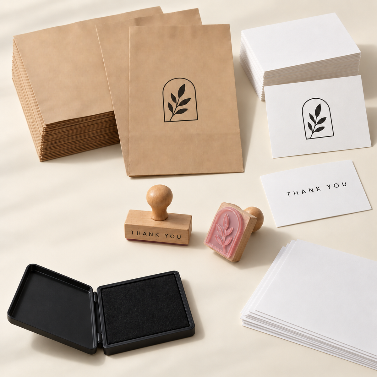 AI concept of the First 50 Orders kit: two wood-mounted logo and thank-you stamps, black ink pad, flat kraft bags, cards and practice sheets shown in representative stacks.